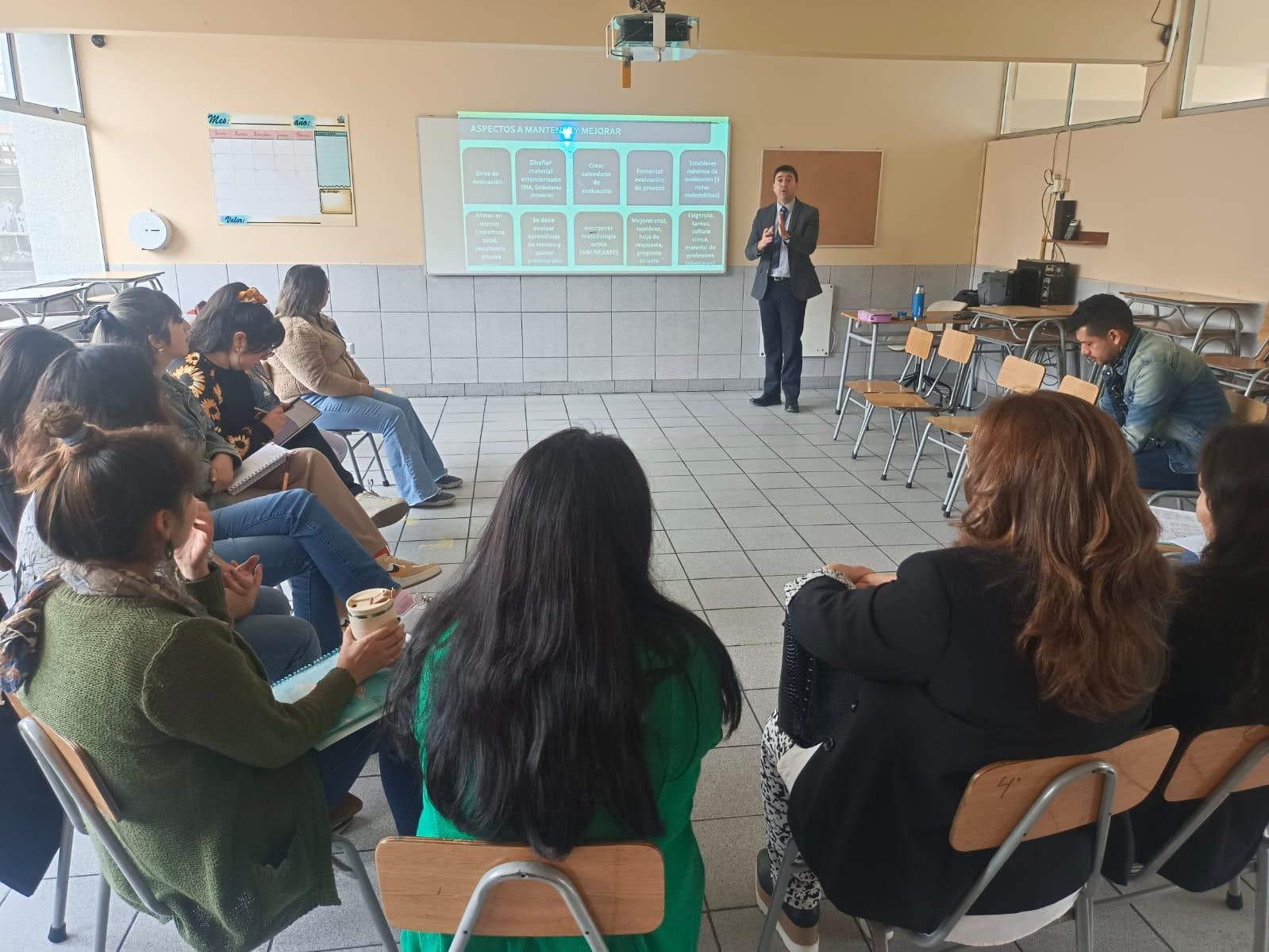Luis Schorwer expone ante un grupo de docentes en una sala de clases, frente a una presentación sobre aspectos a mantener y mejorar